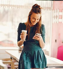 A young female content creator in a bright cafe using her smartphone, symbolizing social media affiliate marketing.