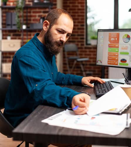 Professional businessman analyzing reports on a laptop in a modern office, representing an Office Garner affiliate partner.